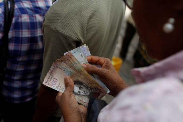 A woman counts Venezuelan bolivar notes at a vegetable street market in Caracas, Venezuela November 13, 2017. REUTERS/Marco Bello