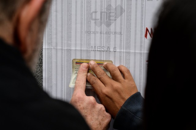 People look for their names on electoral rolls before voting in the municipal elections in Caracas on December 10, 2017. / AFP PHOTO / FEDERICO PARRA