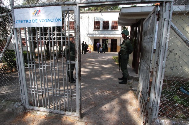 Two members of the Venezuelan military guard the gate to a voting station during the country's municipal elections, in San Cristobal, Tachira state on December 10, 2017. / AFP PHOTO / GEORGE CASTELLANOS