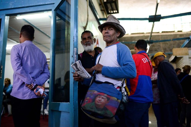 People queue outside the BanPanal communal bank to exchange bolivares for the new local community currency, the panal, launched in the "23 de Enero" working-class neighbourhood in Caracas on December 15, 2017. A collective in a hilltop shantytown in Caracas created its own currency, the panal, in an attempt to fight chronic shortages of cash in inflation-ridden Venezuela. The currency can be exchanged locally for staples like sugar, rice (produced in the neighborhood itself), and bread. / AFP PHOTO / FEDERICO PARRA