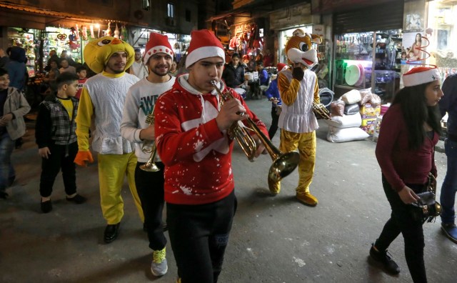 Syrian youths dressed in Christmas outfits and other costumes play trumpets and other musical instruments while roaming the streets of the capital Damascus, as they celebrate Christmas eve on December 24, 2017. / AFP PHOTO / LOUAI BESHARA