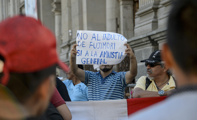 Peruvian citizens living in Chile hold a protest against Peruvian President Pedro Pablo Kuczynski's humanitarian pardon to Peru's jailed ex-president Alberto Fujimori, in Santiago, Chile on December 25, 2017.  Kuczynski on Sunday granted a humanitarian pardon to ex-president Fujimori, who has been hospitalized since Decembre 23 and is serving a 25-year sentence for crimes against humanity. / AFP PHOTO / Martin BERNETTI