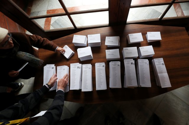 People take ballot papers as they arrive to vote in Catalonia's regional elections at a polling station in Barcelona, Spain December 21, 2017. REUTERS/Albert Gea