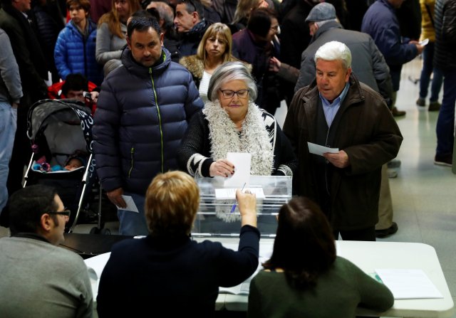 A woman casts her ballot as others wait to vote in Catalonia's regional elections at a polling station in Vic, Spain December 21, 2017. REUTERS/Juan Medina