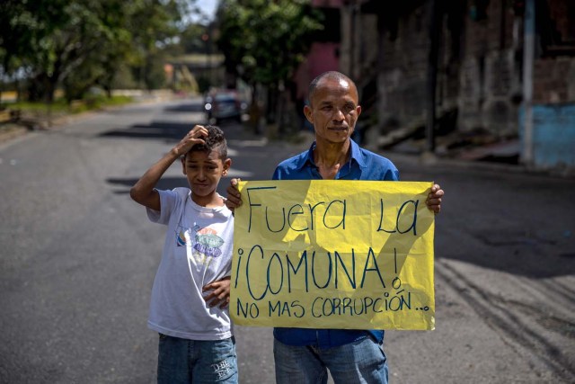 ACOMPAÑA CRÓNICA: VENEZUELA CRISIS. CAR08. CARACAS (VENEZUELA), 27/12/2017.- Un hombre (d) porta un cartel en el que se lee "Fuera de la comuna. No más corrupciión" durante una manifestación hoy, miércoles 27 de diciembre del 2017, en Caracas (Venezuela). Venezuela vive una Navidad con focos de protestas pues en la última semana se han registrado, casi a diario, manifestaciones por falta de "todo" lo que incluye gas doméstico, alimentos y agua, algo que, sumado a la grave crisis económica, ha convertido estas fiestas en "las peores" de los últimos tiempos. EFE/MIGUEL GUTIÉRREZ