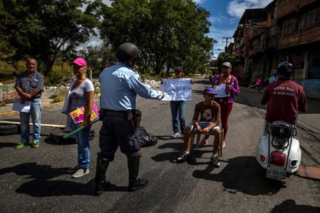 ACOMPAÑA CRÓNICA: VENEZUELA CRISIS. CAR06. CARACAS (VENEZUELA), 27/12/2017.- Un policía habla con un grupo de personas que participa en una manifestación hoy, miércoles 27 de diciembre del 2017, en Caracas (Venezuela). Venezuela vive una Navidad con focos de protestas pues en la última semana se han registrado, casi a diario, manifestaciones por falta de "todo" lo que incluye gas doméstico, alimentos y agua, algo que, sumado a la grave crisis económica, ha convertido estas fiestas en "las peores" de los últimos tiempos. EFE/MIGUEL GUTIÉRREZ