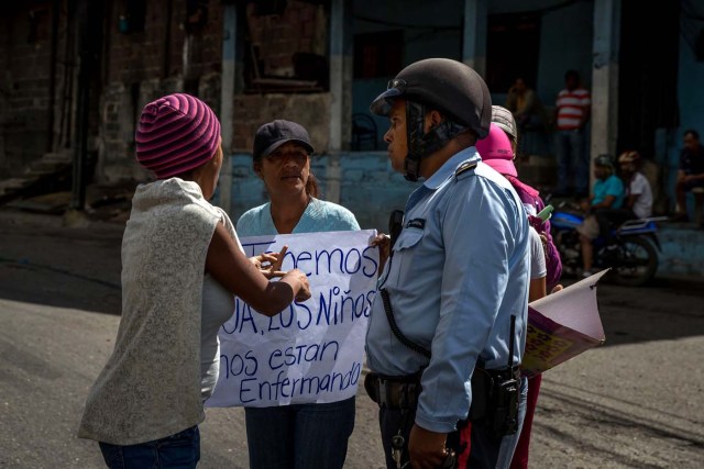 ACOMPAÑA CRÓNICA: VENEZUELA CRISIS. CAR05. CARACAS (VENEZUELA), 27/12/2017.- Un policía habla con un grupo de personas que participa en una manifestación hoy, miércoles 27 de diciembre del 2017, en Caracas (Venezuela). Venezuela vive una Navidad con focos de protestas pues en la última semana se han registrado, casi a diario, manifestaciones por falta de "todo" lo que incluye gas doméstico, alimentos y agua, algo que, sumado a la grave crisis económica, ha convertido estas fiestas en "las peores" de los últimos tiempos. EFE/MIGUEL GUTIÉRREZ