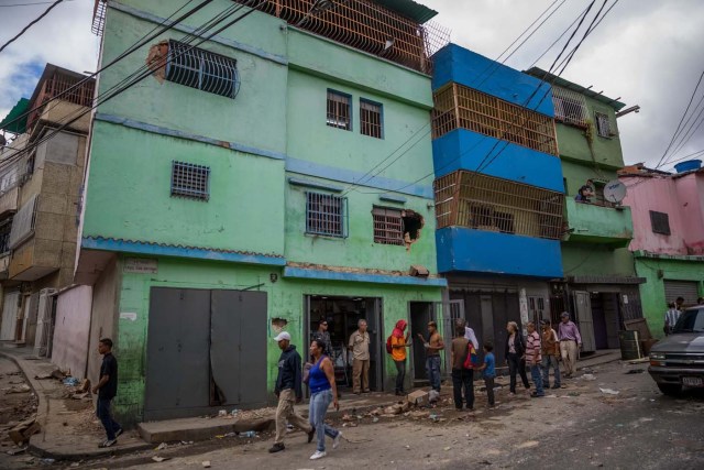 CAR103. CARACAS (VENEZUELA), 28/12/2018.- Un grupo de personas caminan frente a una licorera que fue saqueada en horas de la madrugada en el sector La Vega hoy, jueves 28 de diciembre del 2017, en Caracas (Venezuela). Durante la madrugada de este jueves se registraron en varios puntos de Venezuela protestas por la escasez de alimentos para completar el menú navideño, gas y agua, informaron hoy medios locales. EFE/MIGUEL GUTIÉRREZ