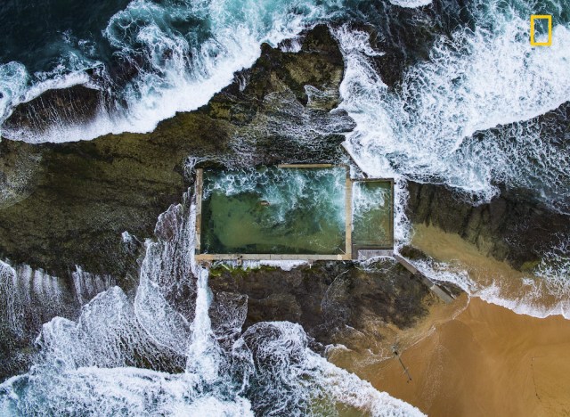 Rock Pool Fotografía ganadora en la categoría: Fotografía aérea En Sydney, Australia, el Océano Pacífico durante la marea alta rompe sobre la costa aportando agua a esta piscina de rocas naturales ampliada en la década de 1930. Evitando las aglomeraciones en las muchas playas de la ciudad, un local disfruta de un baño a solas. Foto: Todd Kennedy / National Geographic Nature Photographer of the Year 2017