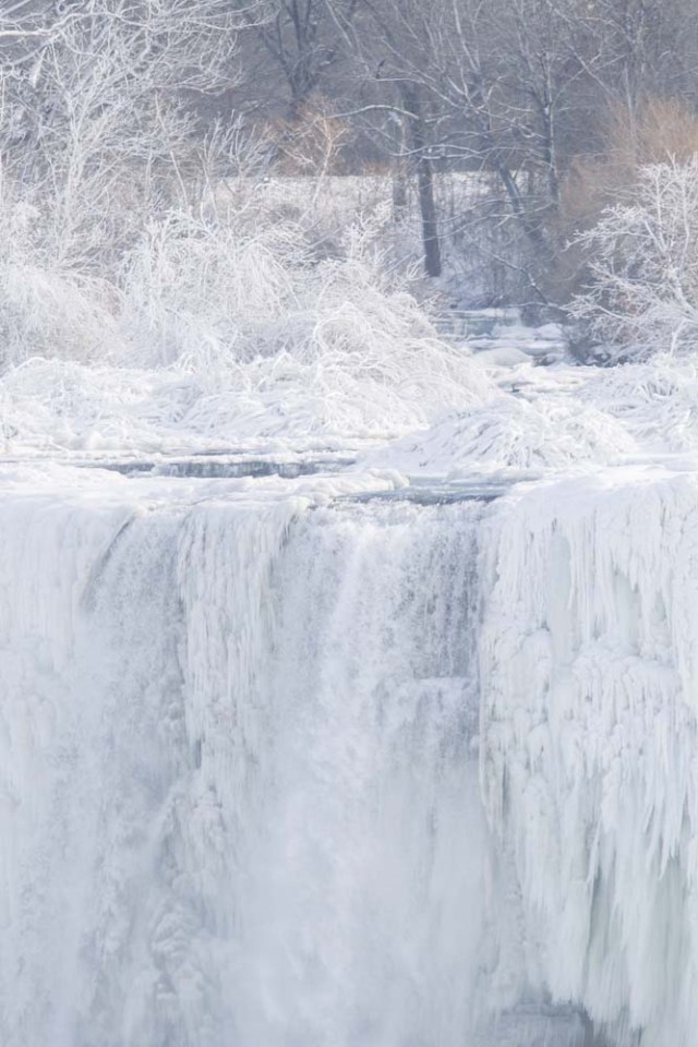 Ice hangs from the top of the American side of Niagara Falls on January 3, 2018 in New York. The cold snap which has gripped much of Canada and the United States has nearly frozen over the American side of the falls. / AFP PHOTO / Geoff Robins