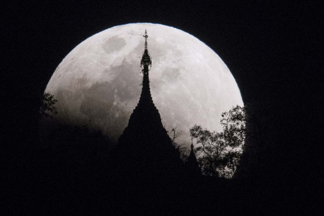 The moon rises over a pagoda in Kumal, some 105 kms away from Mandalay City on January 31, 2018.  Skywatchers were hoping for a rare lunar eclipse that combines three unusual events -- a blue moon, a super moon and a total eclipse -- which was to make for a large crimson moon viewable in many corners of the globe. / AFP PHOTO / YE AUNG THU
