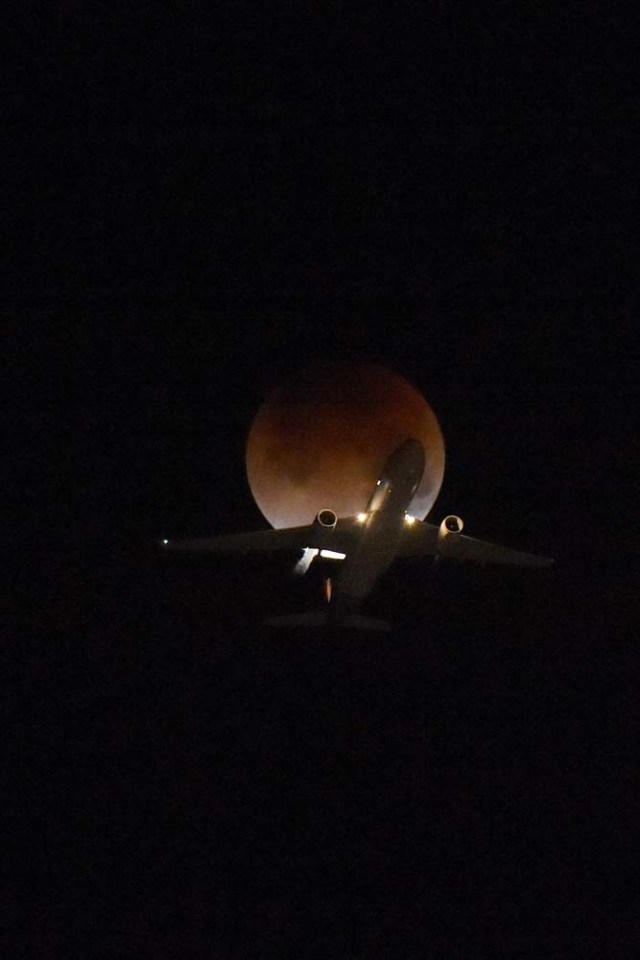 A plane flies passing the moon over Los Angeles, California, on January 31, 2018. Many parts of the globe may catch a glimpse on January 31 of a giant crimson moon, thanks to a rare lunar trifecta that combines a blue moon, a super moon and a total eclipse. The spectacle, which NASA has coined a "super blue blood moon." The celestial show is the result of the sun, Earth, and Moon lining up perfectly for a lunar eclipse just as the Moon is near its closest orbit point to Earth, making it appear "super" large. / AFP PHOTO / Robyn BECK