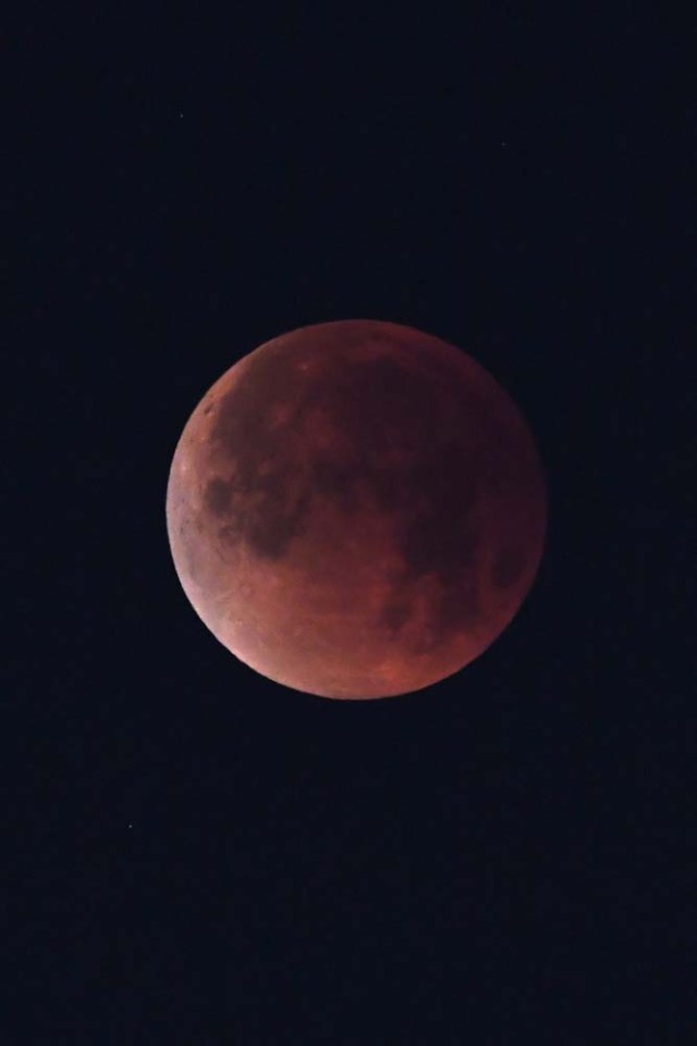 The "super blue blood moon" is seen over Los Angeles, California, on January 31, 2018. Many parts of the globe may catch a glimpse on January 31 of a giant crimson moon, thanks to a rare lunar trifecta that combines a blue moon, a super moon and a total eclipse. The spectacle, which NASA has coined a "super blue blood moon." The celestial show is the result of the sun, Earth, and Moon lining up perfectly for a lunar eclipse just as the Moon is near its closest orbit point to Earth, making it appear "super" large. / AFP PHOTO / Robyn Beck