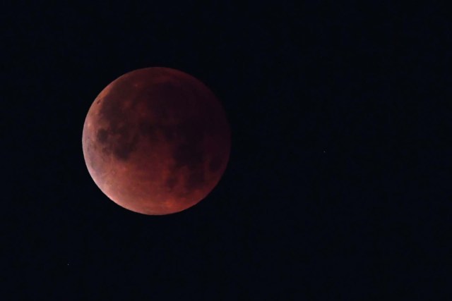 The "super blue blood moon" is seen over Los Angeles, California, on January 31, 2018. Many parts of the globe may catch a glimpse on January 31 of a giant crimson moon, thanks to a rare lunar trifecta that combines a blue moon, a super moon and a total eclipse. The spectacle, which NASA has coined a "super blue blood moon." The celestial show is the result of the sun, Earth, and Moon lining up perfectly for a lunar eclipse just as the Moon is near its closest orbit point to Earth, making it appear "super" large. / AFP PHOTO / Robyn Beck