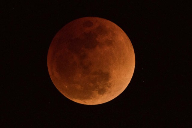 The moon is seen during a lunar eclipse, referred to as the "super blue blood moon", in Beijing on January 31, 2018. / AFP PHOTO / NICOLAS ASFOURI