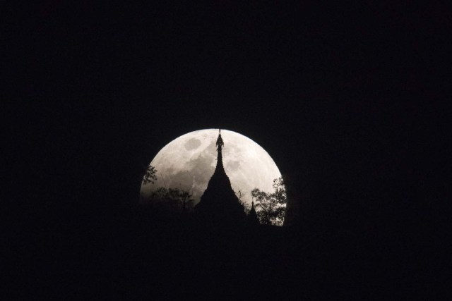 The moon rises over a pagoda in Kumal, some 105 kms away from Mandalay City on January 31, 2018. Skywatchers were hoping for a rare lunar eclipse that combines three unusual events -- a blue moon, a super moon and a total eclipse -- which was to make for a large crimson moon viewable in many corners of the globe. / AFP PHOTO / YE AUNG THU