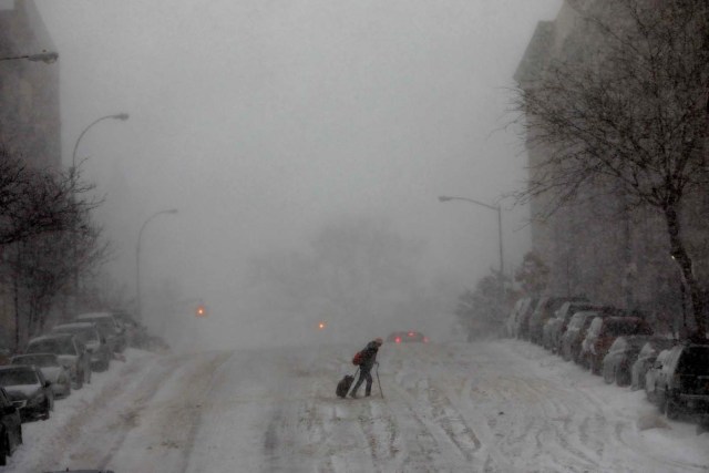 A woman struggles across a snow-covered 145th Street in upper Manhattan during a snowstorm in New York City, New York, U.S., January 4, 2018. REUTERS/Mike Segar