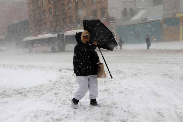 A woman struggles against wind and snow as she crosses 125th street in upper Manhattan during a snowstorm in New York City, New York, U.S., January 4, 2018. REUTERS/Mike Segar