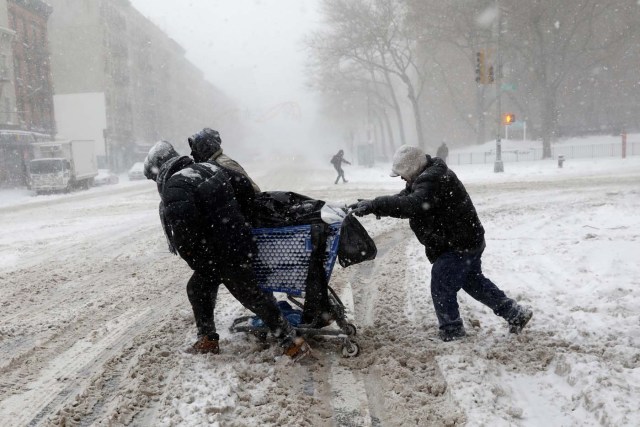 Men struggle against wind and snow as they push a shopping cart across 125th street in upper Manhattan during a snowstorm in New York City, New York, U.S., January 4, 2018. REUTERS/Mike Segar