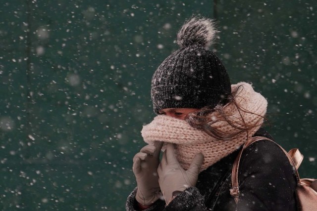 A woman covers her face as she walks though Times Square during a snowstorm in New York City, New York, U.S., January 4, 2018. REUTERS/Carlo Allegri