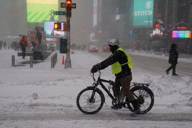 A delivery person on a bicycle makes his way though Times Square during Storm Grayson in New York City, New York, U.S., January 4, 2018. REUTERS/Carlo Allegri