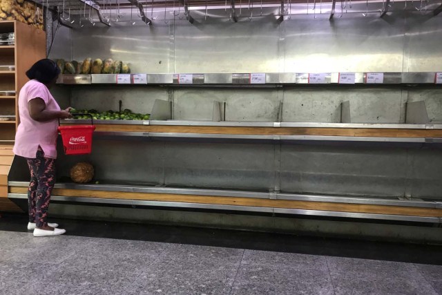 A woman selects lemons from partially empty shelves at the fruits and vegetables area in a supermarket in Caracas, Venezuela January 10, 2018. REUTERS/Marco Bello