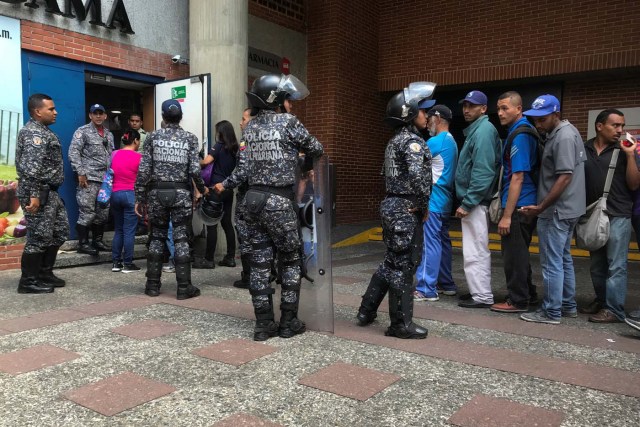 Police officers control the crowd as people line up to buy sugar, outside a supermarket in Caracas, Venezuela January 10, 2018. REUTERS/Marco Bello