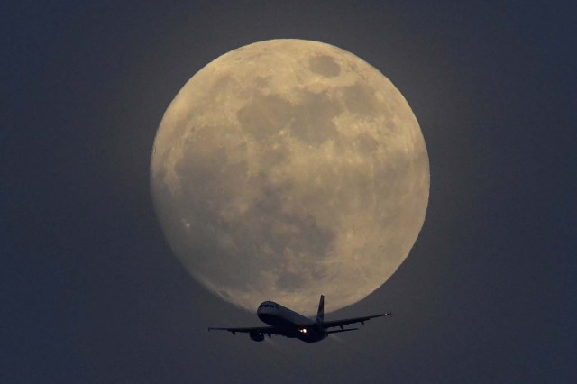 A British Airways aicraft flies infront of a full moon over London, Britain, January 30, 2018. REUTERS/Toby Melville