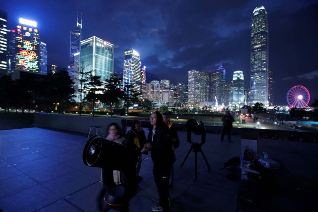 People set up telescopes in front of the financial Central district for the super blue moon and eclipse in Hong Kong, China January 31, 2018. REUTERS/Bobby Yip