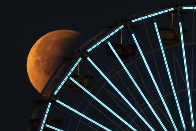 A lunar eclipse of a full "Blue Moon" is seen above the ferris wheel on the Santa Monica Pier in Santa Monica, California, U.S., January 31, 2018. REUTERS/Lucy Nicholson