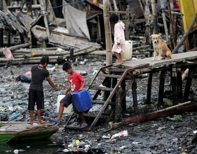  Las Pinas City (Philippines), 01/01/2018.- Filipino residents carry containers to collect potable water at a fishing village in Las Pinas city, south of Manila, Philippines, 02 January 2018. According to latest forecast from the Philippine Atmospheric Geophysical and Astronomical Services Administration (PAGASA), heavy rains are expected as Tropical Depression Agaton is crossing the country packing maximum winds of up to 55kph with gusts of 90kph. (Filipinas) EFE/EPA/FRANCIS R. MALASIG