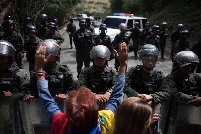 CAR016. CARACAS (VENEZUELA), 20/01/2018. Miembros de la Guardia Nacional Bolivariana (GNB) custodian una parcela del Cementerio del Este y cercan el paso a familiares de José Díaz Pimentel y a Abraham Agostini hoy, sábado 20 de enero del 2018, en Caracas (Venezuela). Dos de las seis personas abatidas junto al exinspector alzado contra el Gobierno venezolano Óscar Pérez fueron enterrados hoy en medio de denuncias de que los familiares no autorizaron el sepelio, mientras continúa la incertidumbre sobre qué se hará con el cuerpo del líder del grupo. EFE/Miguel Gutiérrez