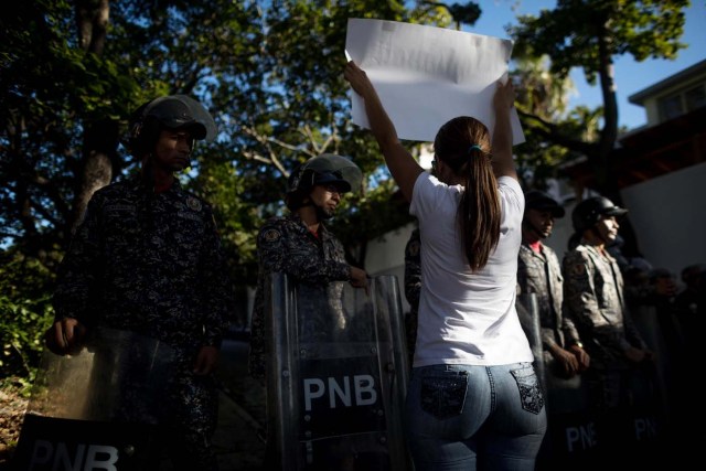 CAR205. CARACAS (VENEZUELA), 20/01/2018.- Miembros de la Policía Nacional Bolivariana (PNB) custodian las inmediaciones de la morgue mientras personas protestan en apoyo a los familiares de Oscar Pérez hoy, sábado 20 de enero del 2018, en Caracas (Venezuela). Cientos de venezolanos honraron hoy al exinspector de la Policía científica Óscar Pérez y a sus seis compañeros, que murieron el lunes en una operación policial, en medio de la tensión que ha generado la entrega del cuerpo del líder del grupo que se alzó contra el Gobierno de Nicolás Maduro. EFE/Miguel Gutiérrez