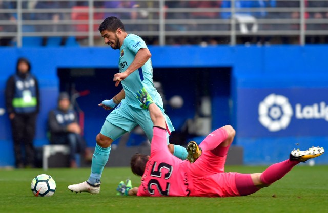 Barcelona's Uruguayan forward Luis Suarez (L) dodges Eibar's Portuguese Serbian goalkeeper Marko Dmitrovic to score a goal during the Spanish league football match between SD Eibar and FC Barcelona at the Ipurua stadium in Eibar on February 17, 2018. / AFP PHOTO / ANDER GILLENEA