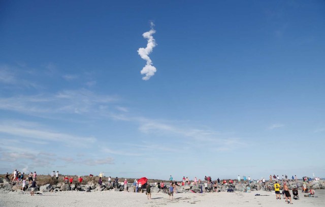The contrail of SpaceX's first Falcon Heavy rocket loom above spectators at Cocoa Beach after its launch from the Kennedy Space Center, Florida, U.S., February 6, 2018. REUTERS/Gregg Newton