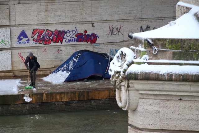 A man removes snow from his tent near the river Tiber after a heavy snowfall in Rome, Italy February 26, 2018. REUTERS/Alessandro Bianchi