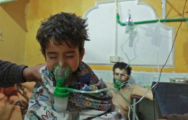 Syrian children and adults receive treatment for a suspected chemical attack at a makeshift clinic on the rebel-held village of al-Shifuniyah in the Eastern Ghouta region on the outskirts of the capital Damascus late on February 25, 2018. A child died and at least 13 other people suffered breathing difficulties after a suspected chemical attack on the besieged Syrian rebel enclave, a medic and a monitor said. The Britain-based Syrian Observatory for Human Rights said 14 civilians had suffered breathing difficulties after a regime warplane struck the village. / AFP PHOTO / HAMZA AL-AJWEH