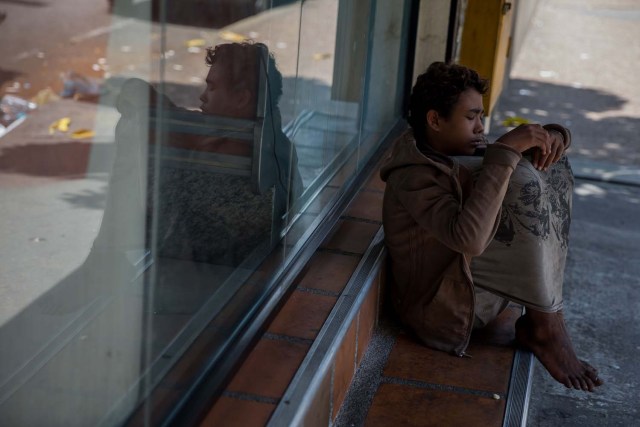 Fotografía del 3 de marzo de 2018 de un adolescente en la entrada de una panadería en Caracas (Venezuela). La inédita crisis económica y social de Venezuela se hace inocultable en calles y casas de abrigo que a diario reciben a niños que han quedado desamparados después de que sus padres emigraran a otro país a buscar nuevas formas de ingresos y los dejaran a cargo de personas que no pueden mantenerlos. EFE/MIGUEL GUTIÉRREZ