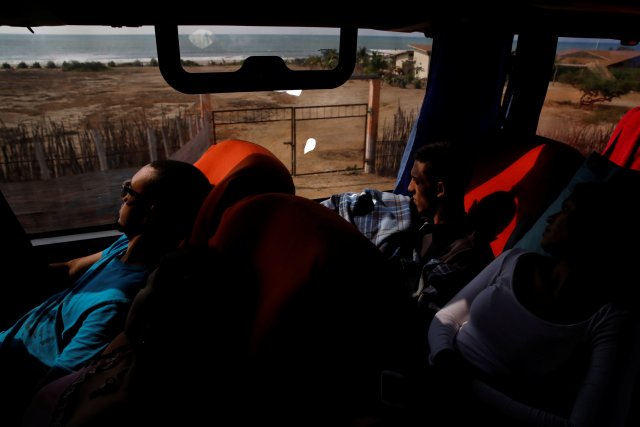 Carlos Rivero (L) y Adrián Naveda (C), viajando en autobús desde Caracas a Chile, miran por la ventana mientras conducen por Zorritos, Perú, el 11 de noviembre de 2017. "Creo que esperamos demasiado para irnos" dijo Carlos Rivero, 31, ex operador de seguridad del metro de Caracas. El camino por el que viaja el autobús en el norte de Perú pasa a través de pequeños pueblos cerca de la orilla del mar. REUTERS / Carlos Garcia Rawlins