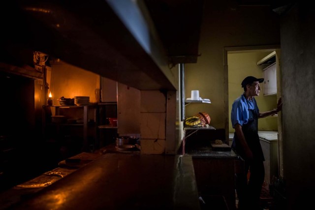 CAR202. CARACAS (VENEZUELA), 05/03/2018.- Un asistente de cocina observa por una ventana en un restaurante durante una falla eléctrica hoy, lunes 5 de marzo de 2018, en Caracas (Venezuela). Un fallo eléctrico del que se desconocen por ahora los detalles ha dejado sin luz a la capital venezolana, Caracas, por tercera vez en tres meses, y 10 días después de otro apagón que afectó a una decena de estados del país petrolero. EFE/MIGUEL GUTIÉRREZ