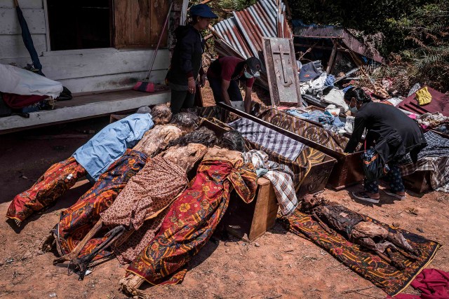 PIC BY Claudio Sieber / CATERS NEWS - (PICTURED The family is taking care of their deceased relatives during the ritual of MaNene.)THESE images show a unique insight into the village where the living dig up their dead relatives to clean their bones and to dress them up. The dead can even remain in homes for decades until the family throw a huge party in their honour. The corpses are treated as sick until they finally find peace after funeral rites known as Rambu Solo The bizarre ritual was pictured in South Sulawesi, Indonesia, where even buried relatives are taken out of their coffins for new outfits and a bone polish. SEE CATERS COPY