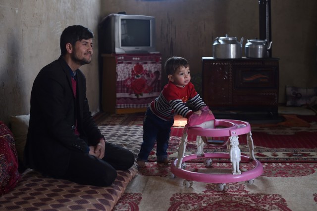 This picture taken on March 16, 2018 shows Afghan father Sayed Assadullah Pooya, 28, looking on alongside his son Donald Trump, aged around 18 months, during an interview with AFP at their home in Kabul. Donald Trump flops over his pink and white baby walker and rolls it around the unfurnished room in Kabul, blissfully unaware of the turmoil his "infidel" name is causing in the conservative Muslim country. The rosy-cheeked toddler, whose parents named him after the more famous Donald Trump in the hope of replicating his success, is at the centre of a social media firestorm after a photo of his Afghan ID papers was posted on Facebook. / AFP PHOTO / Wakil KOHSAR / TO GO WITH 'AFGHANISTAN-PEOPLE-RELIGION' BY ALLISON JACKSON AND MUSHTAQ MOJADDIDI