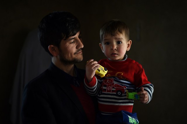 This picture taken on March 16, 2018 shows Afghan father Sayed Assadullah Pooya, 28, posing for a photograph with his son Donald Trump, aged around 18 months, at their home in Kabul. Donald Trump flops over his pink and white baby walker and rolls it around the unfurnished room in Kabul, blissfully unaware of the turmoil his "infidel" name is causing in the conservative Muslim country. The rosy-cheeked toddler, whose parents named him after the more famous Donald Trump in the hope of replicating his success, is at the centre of a social media firestorm after a photo of his Afghan ID papers was posted on Facebook. / AFP PHOTO / Wakil KOHSAR / TO GO WITH 'AFGHANISTAN-PEOPLE-RELIGION' BY ALLISON JACKSON AND MUSHTAQ MOJADDIDI