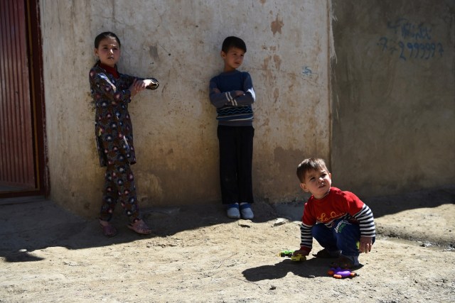 This picture taken on March 16, 2018 shows Afghan toddler Donald Trump (R), who is aged around 18 months, playing with his sister Fatemah (C), 8, and his brother Kareem, 9, at their home in Kabul. Donald Trump flops over his pink and white baby walker and rolls it around the unfurnished room in Kabul, blissfully unaware of the turmoil his "infidel" name is causing in the conservative Muslim country. The rosy-cheeked toddler, whose parents named him after the more famous Donald Trump in the hope of replicating his success, is at the centre of a social media firestorm after a photo of his Afghan ID papers was posted on Facebook. / AFP PHOTO / Wakil KOHSAR / TO GO WITH 'AFGHANISTAN-PEOPLE-RELIGION' BY ALLISON JACKSON AND MUSHTAQ MOJADDIDI