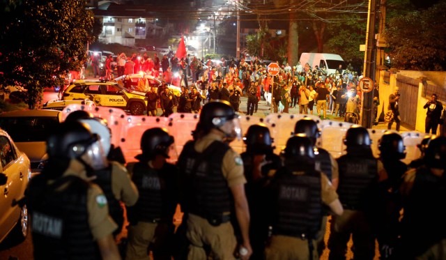 Supporters of former Brazilian President Luiz Inacio Lula da Silva are seen behind riot police in front of the Federal Police headquarters, in Curitiba, Brazil, April 7, 2018. REUTERS/Rodolfo Buhrer