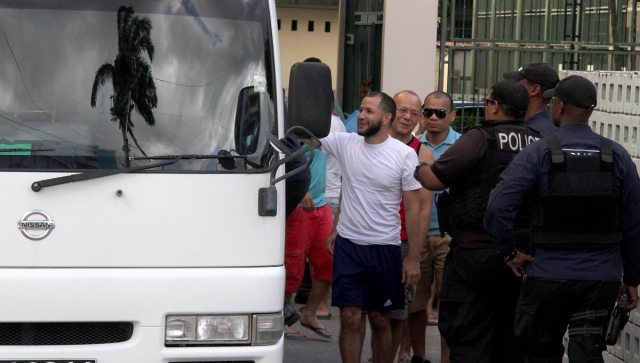 Es hora de irse: los policías guían a los detenidos venezolanos a un autobús después de que fueron procesados en la Embajada de Venezuela en Puerto España el viernes. Foto de Roger Jacob en Newsday