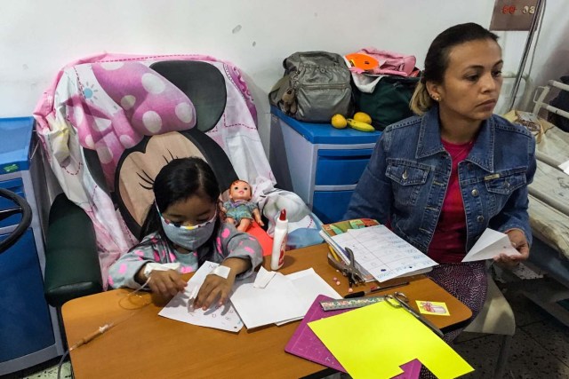 A girl plays as she receives chemotherapy at the "Dr. JM de los Rios" Children's Hospital in Caracas on April 10, 2018. The crisis in Venezuela has hit children's health, with an increase of 30,12% in child mortality according to the most recent official sources. / AFP PHOTO / FEDERICO PARRA