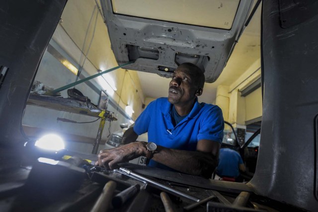 Venezuelan Hugo Alexander works at a locksmith's car shop in Montevideo on May 10, 2018. Exiled Venezuelans have no expectations of the presidential election taking place next May 20 in their home country. / AFP PHOTO / MIGUEL ROJO