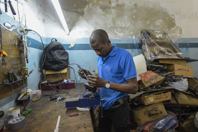 Venezuelan Hugo Alexander works at a locksmith's car shop in Montevideo on May 10, 2018. Exiled Venezuelans have no expectations of the presidential election taking place next May 20 in their home country. / AFP PHOTO / MIGUEL ROJO