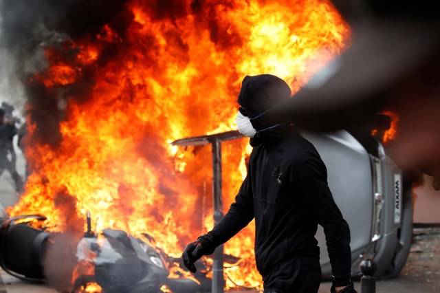 Un manifestante enmascarado camina cerca de un automóvil que se quema frente a un garaje de un automóvil de Renault durante enfrentamientos durante la marcha sindical del Primero de Mayo en París, Francia, el 1 de mayo de 2018. REUTERS / Christian Hartmann